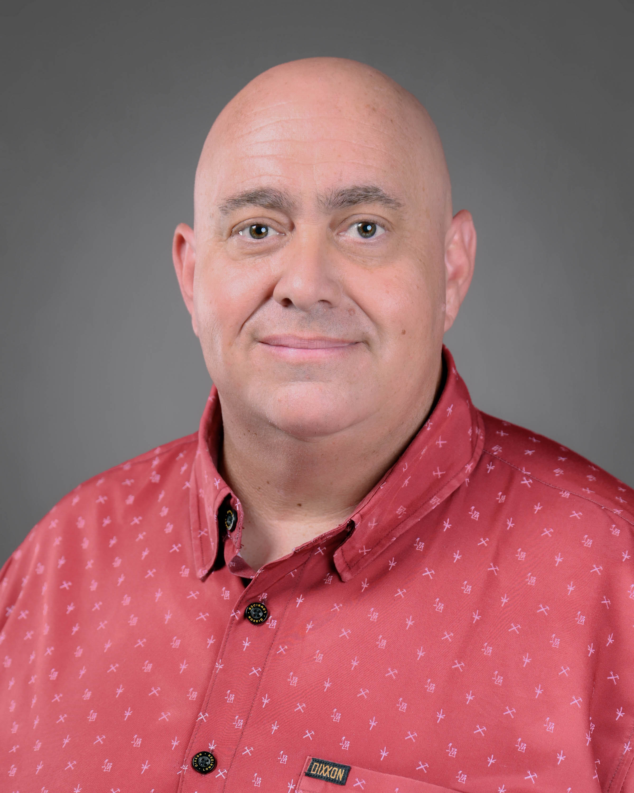 Clean cut and clean-shaven man in a red collared shirt.